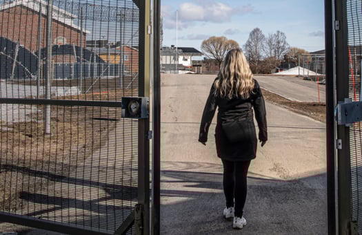 En kvinna som går in genom en halvöppen säkerhetsgrind.