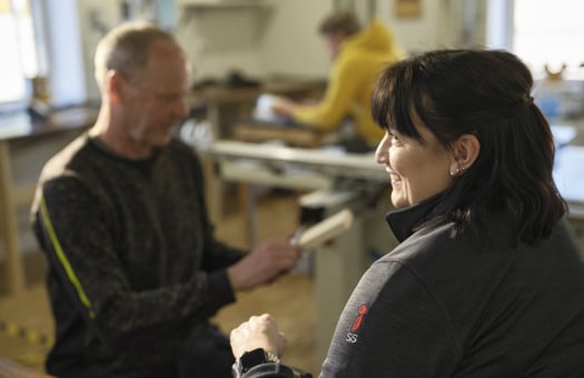 En lärare håller träslöjdslektion för fiktiv elev i ett klassrum.