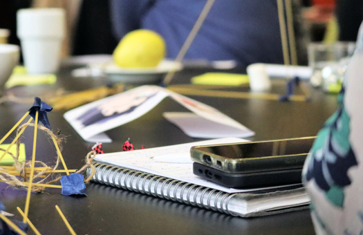 Bild på ett konferensbord med bland annat block, pennor och två mobiltelefoner.
