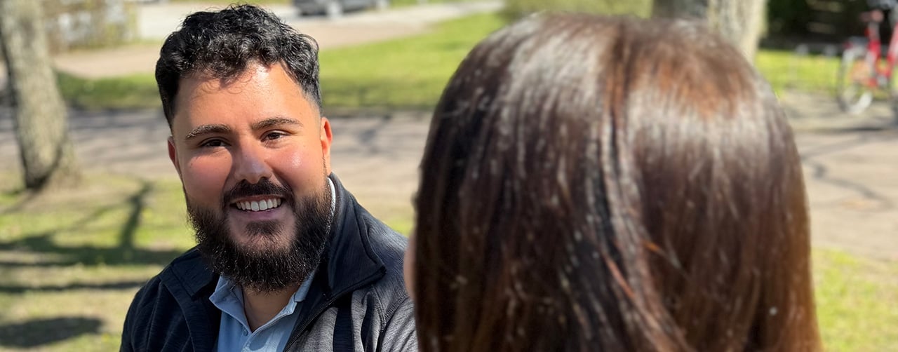 Bild på Ahmad som sitter utomhus i solen tillsammans med en kollega som man ser bakifrån.