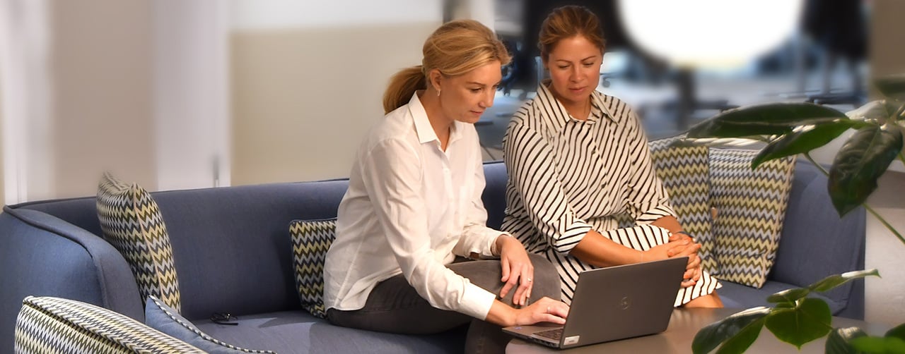 Medarbetare som jobbar tillsammans vid en dator i en soffgrupp.