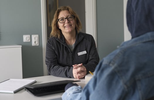 En lärare sitter tillsammans med en elev vid ett arbetsbord.