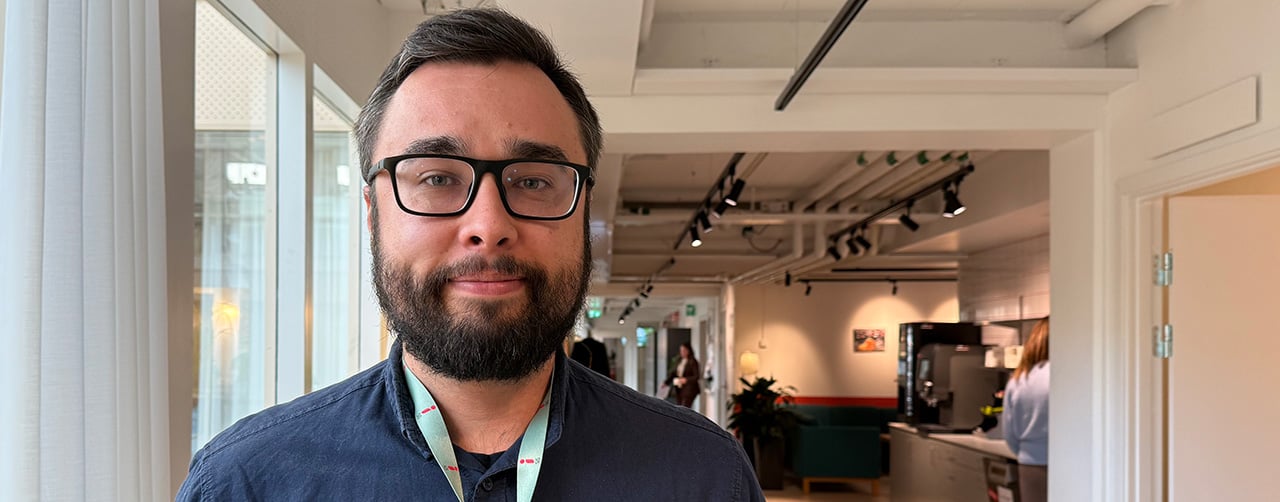 Bild på Mattias Enbacka med ett kontorslandskap i bakgrunden.