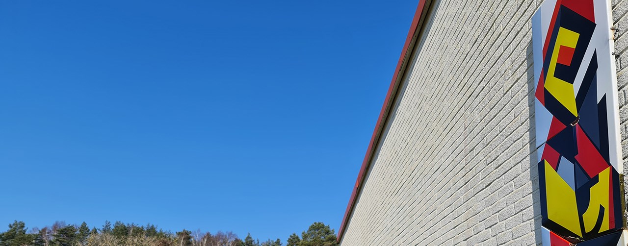 Vägg med målning i klara färger framför en blå himmel