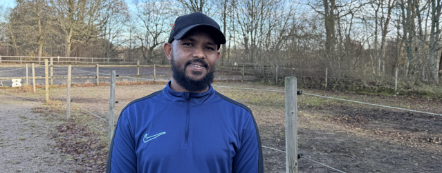 Bild på behandlingsassistent Suleiman som står i en hästhage.