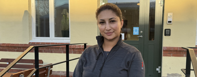 Bild på behandlingspedagogen Yasmin som står framför ett gult hus.