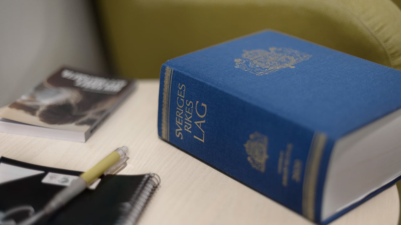 En lagbok som ligger på ett bord med ett block och en penna.